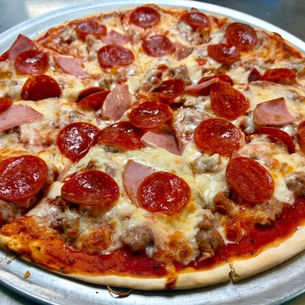 Delicious meat lover's pizza with pepperoni, ham, and sausage on a metal tray.